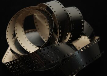 Koyu arka plan üzerinde birbirine sarılmış siyah beyaz film şeridi.