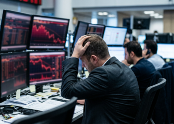 Borsa düşüşü karşısında endişeyle başını tutan bir yatırımcı ve ekranlar.