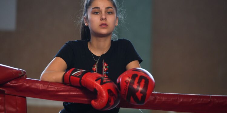 Kırmızı boks eldivenleri takmış, köşede kollarını yaslamış duran kadın boksör.
