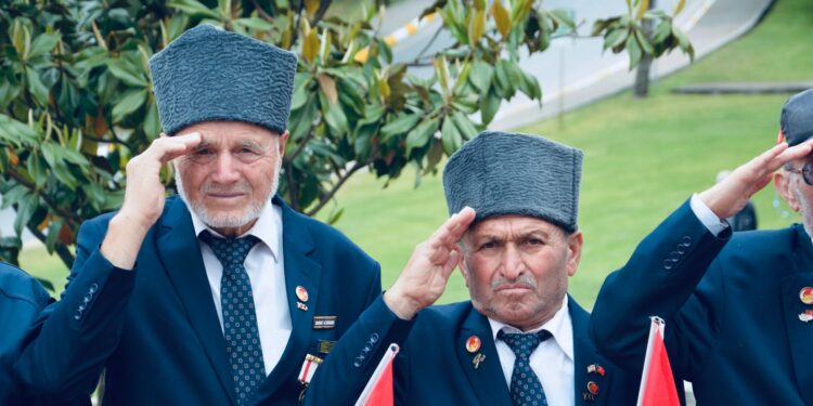 Geleneksel kıyafetler giymiş ve törende selam duran yaşlı gaziler.