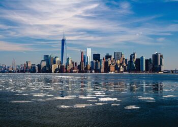 Açık mavi gökyüzü altında buzlu deniz sularının arkasında yükselen New York silüeti.