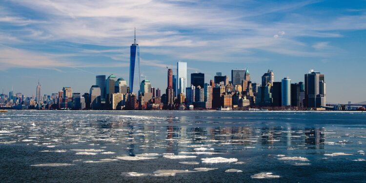 Açık mavi gökyüzü altında buzlu deniz sularının arkasında yükselen New York silüeti.