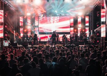 Açık hava konser alanında sahne ışıkları altında performans sergileyen müzik grubu.