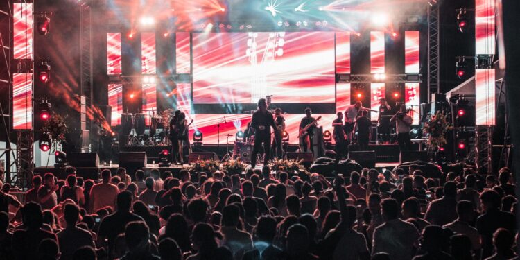 Açık hava konser alanında sahne ışıkları altında performans sergileyen müzik grubu.