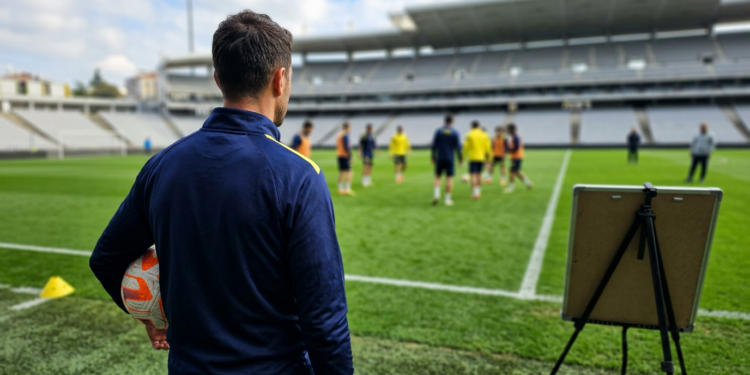 Futbol sahasında antrenman yöneten teknik direktör ve futbolcular.