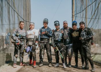 Açık alanda paintball ekipmanları giymiş, silahlı ve hazırlıklı erkek grup.