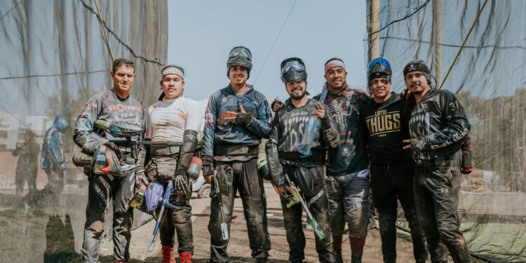 Açık alanda paintball ekipmanları giymiş, silahlı ve hazırlıklı erkek grup.