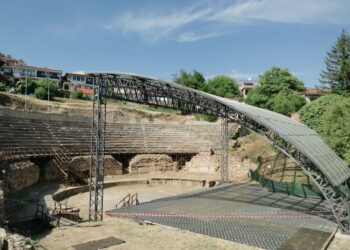 Tarihi antik tiyatro sahnesi ve oturma basamakları altında mavi gökyüzü.