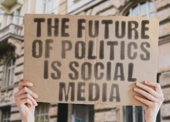 Üzerinde 'The future of politics is social media' yazan karton tabela tutan eller
