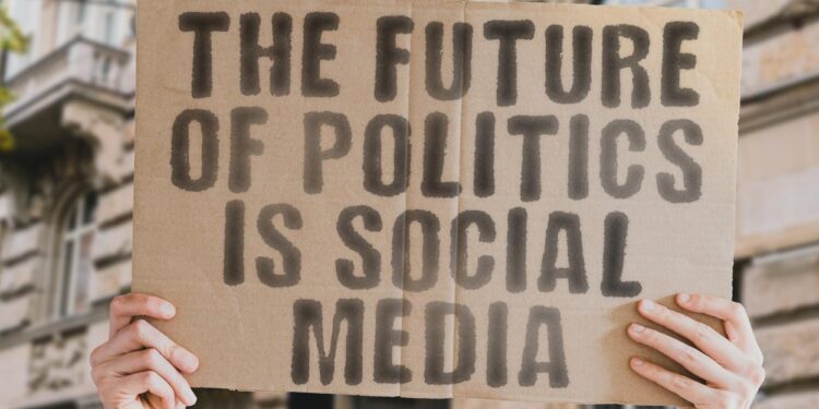 Üzerinde 'The future of politics is social media' yazan karton tabela tutan eller