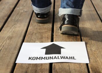 Ahşap zemin üzerinde kommunalwahl yazılı yön oku ve yürüyen ayaklar.