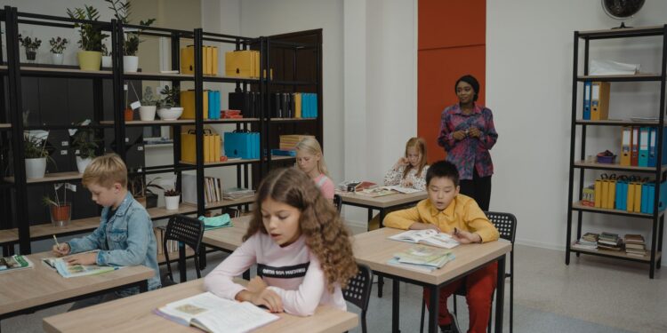 Sınıfta ders işleyen öğrenciler ve tahtanın önünde duran öğretmen