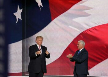 ABD bayrağı önünde duran Donald Trump ve yanında alkışlayan Mike Pence.