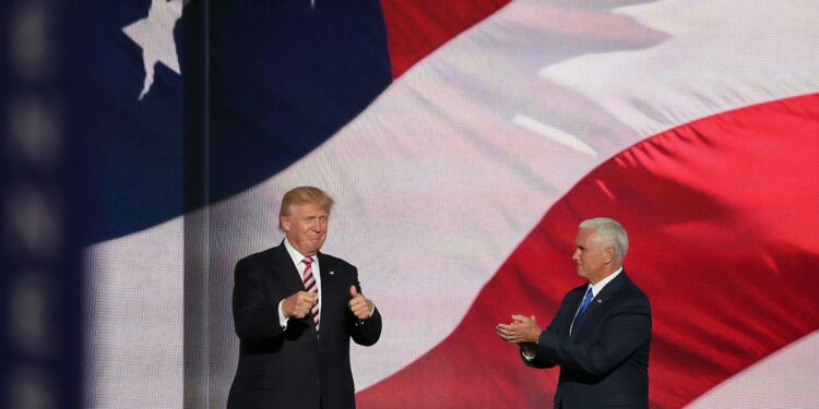 ABD bayrağı önünde duran Donald Trump ve yanında alkışlayan Mike Pence.