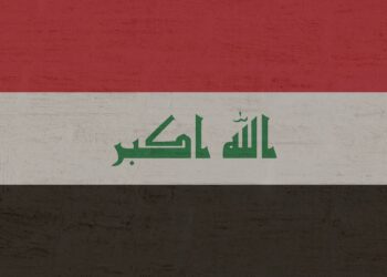 Kırmızı, beyaz ve siyah şeritli ortasında Arapça yazı olan Irak bayrağı.