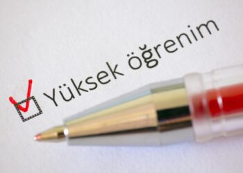 Kırmızı tükenmez kalemle yükseköğrenim kutucuğunun işaretlendiği beyaz kağıt yakın çekim.