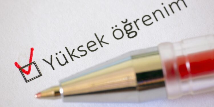 Kırmızı tükenmez kalemle yükseköğrenim kutucuğunun işaretlendiği beyaz kağıt yakın çekim.