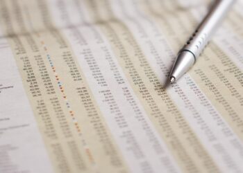 Detaylı finansal tablo ve borsa verilerinin üzerine yerleştirilmiş tükenmez kalem.
