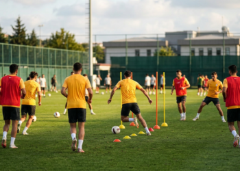 Futbolcular antrenman sahasında top sürme ve koordinasyon çalışması yapıyorlar.