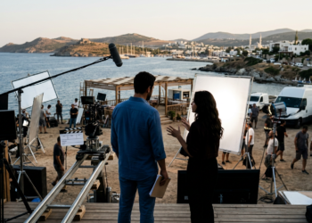 Deniz kenarında film seti arkasında yönetmen ve oyuncu çalışıyor.